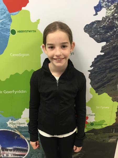 A girl standing infront of a map of Wales